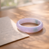 Pale icy jade bangle placed beside a handwritten note in soft morning light, symbolizing love, memory, and cultural meaning.