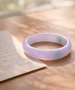 Pale icy jade bangle placed beside a handwritten note in soft morning light, symbolizing love, memory, and cultural meaning.